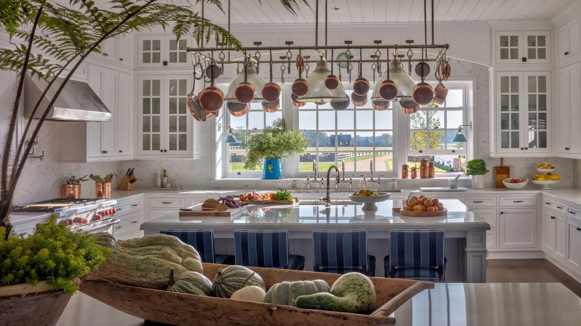 Private chef preparing gourmet meal in luxury villa kitchen with concierge arranging flowers in background