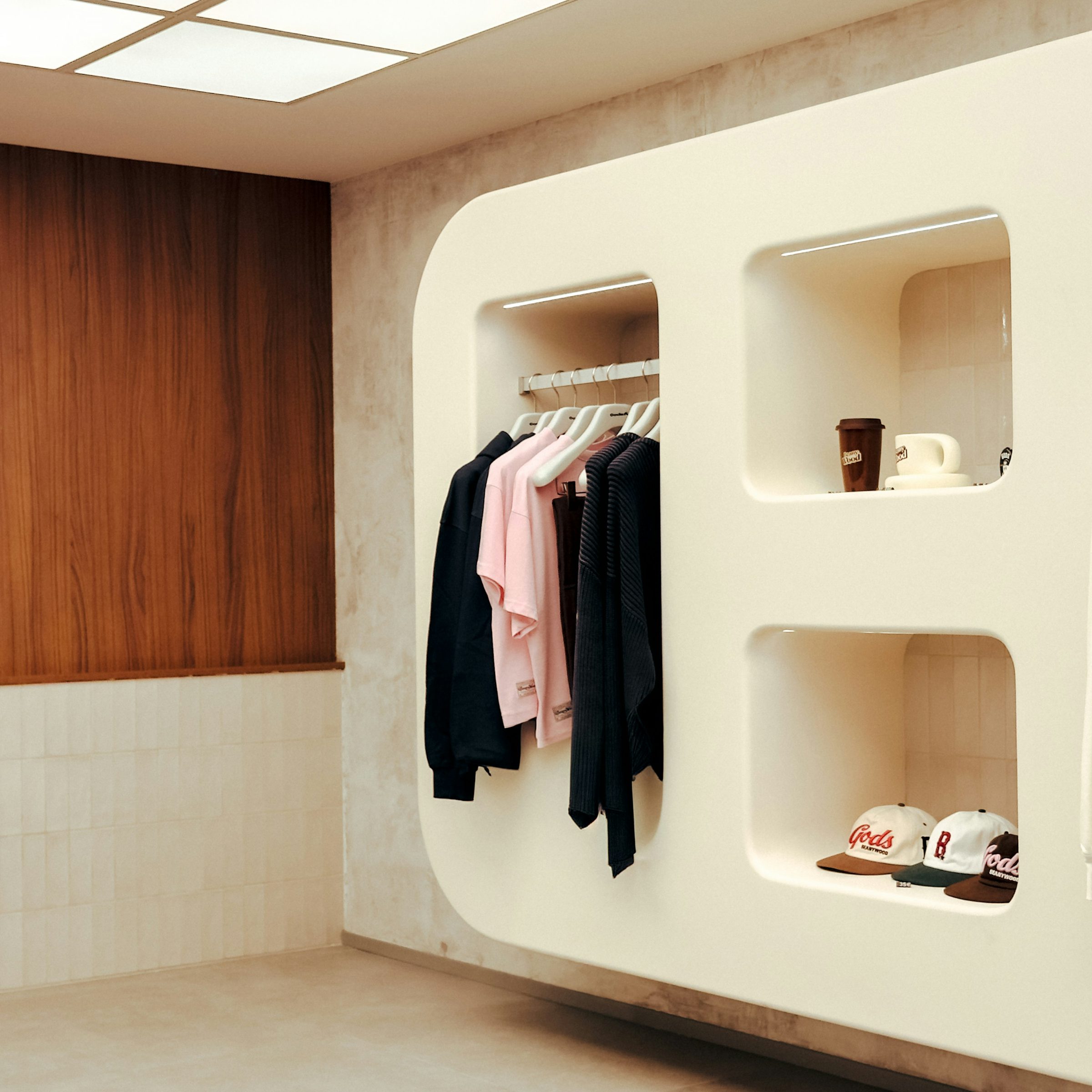 Ankleidezimmer in Cremetönen mit hängenden Kleidungsstücken und Nischen